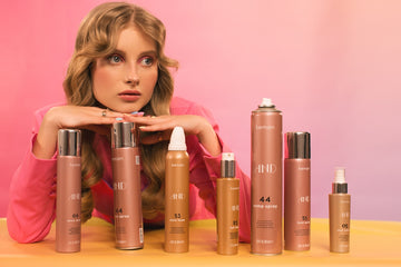 Young woman looks at multiple hair product bottles